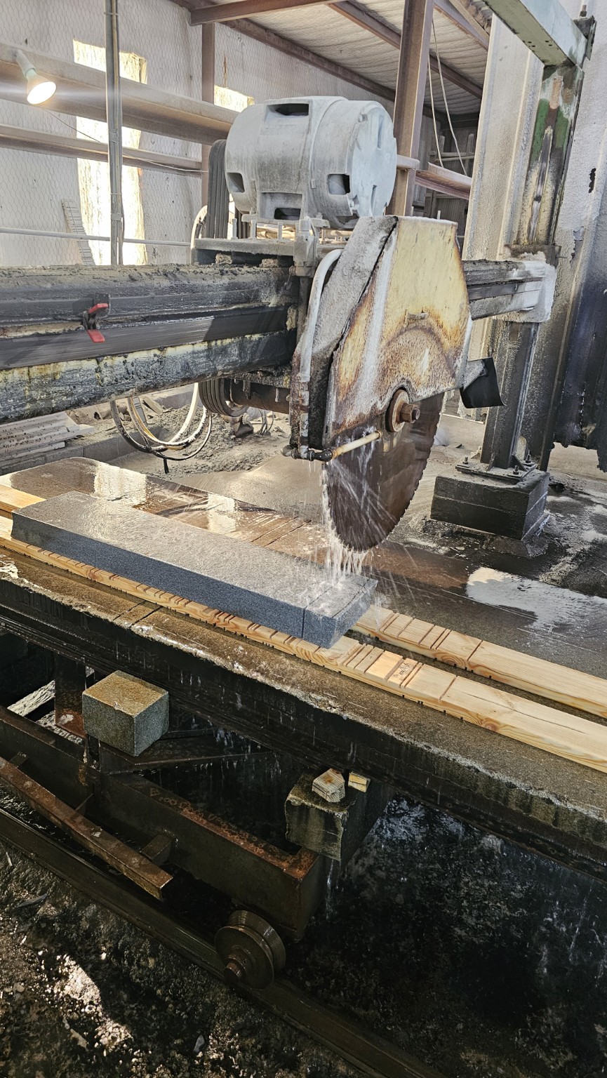 Water-cooled circular saw cutting a granite slab at the manufacturing partner’s factory