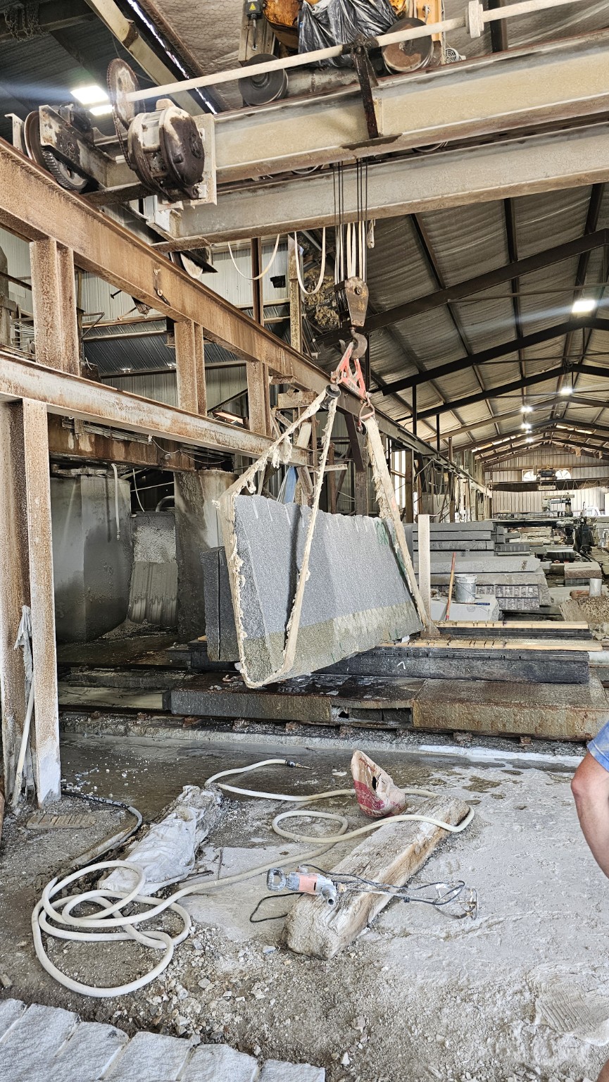 Overhead crane lifting a granite slab inside the factory