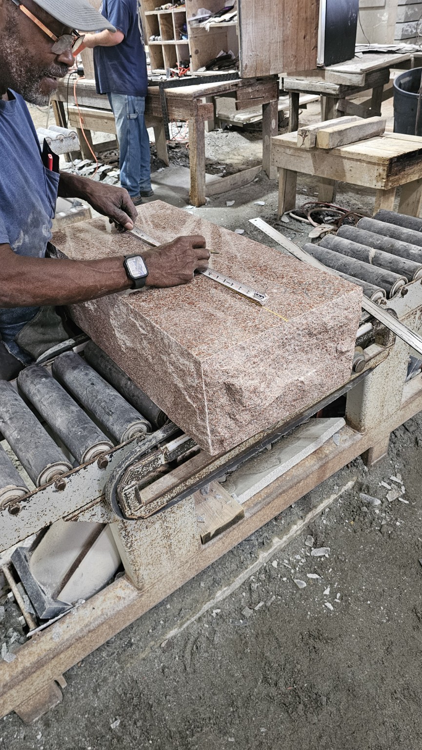 Craftsperson measuring and marking a pink granite block