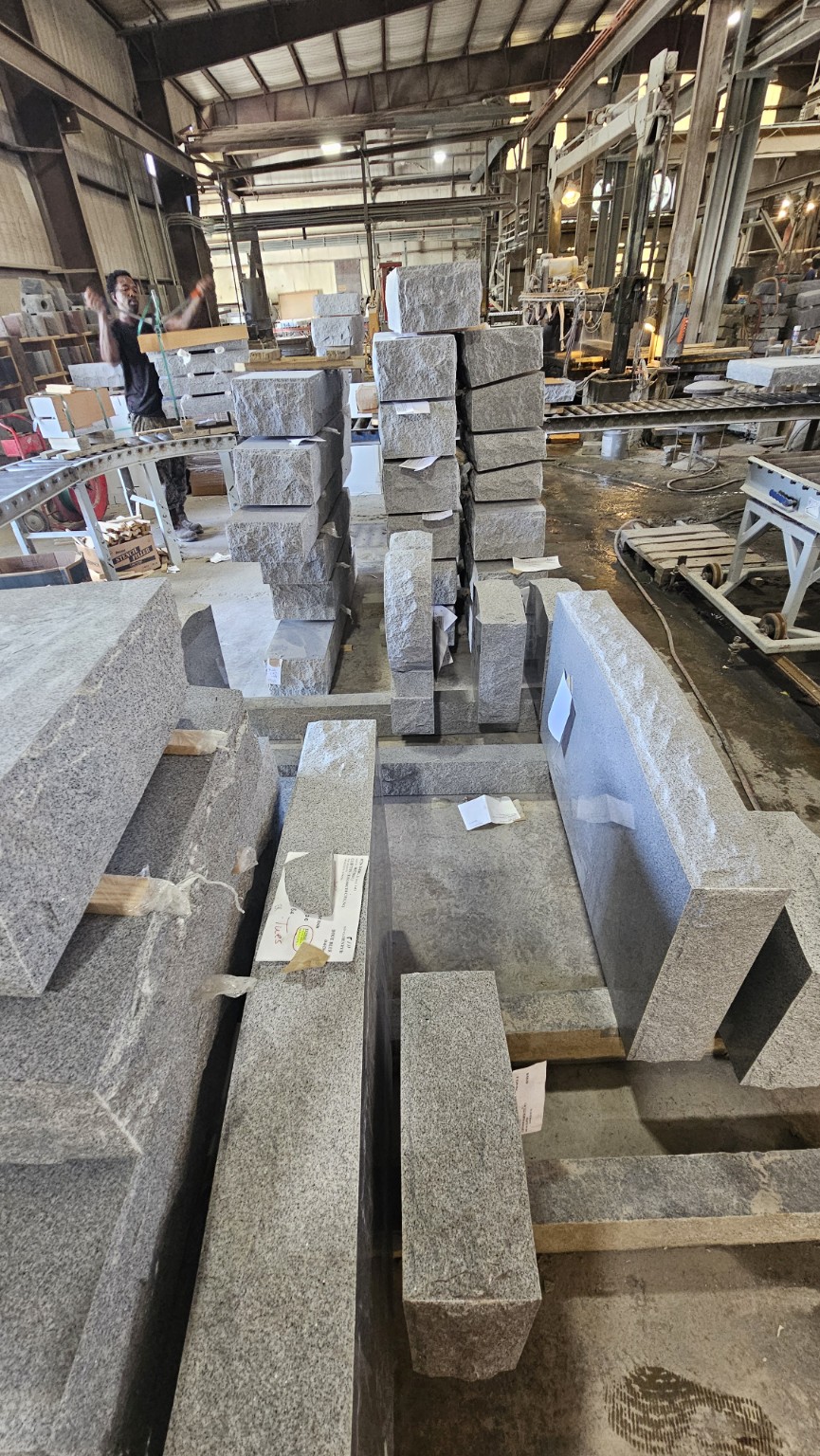 Rows of shaped granite memorials and stone pieces on the factory floor